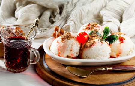 vanilla ice cream with cherry and mint on a white plate.の写真素材