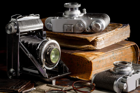 Vintage camera, books and glasses on a black background close-up