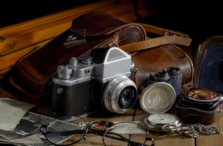 Vintage camera and old photos on a wooden table. Black background.の写真素材