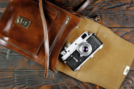 Vintage camera and leather bag on wooden background. Top view.の写真素材