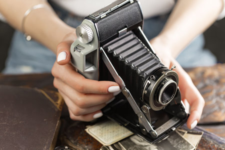 A girl with a beautiful manicure holds an old camera in her hands.の写真素材