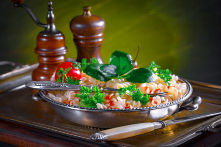 Fusilli pasta with tomato and parsley on a metal trayの写真素材