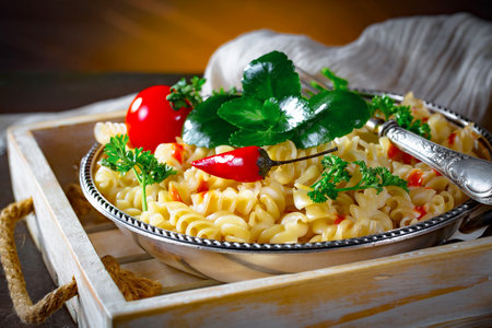 Fusilli pasta with tomato and parsley on a wooden trayの写真素材