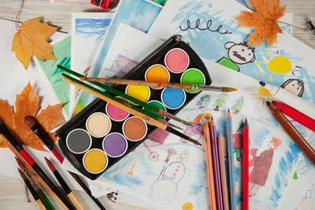 Paints, brushes and autumn leaves on a white wooden background.の写真素材