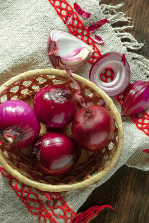Red onions in a basket on a napkin on a wooden backgroundの写真素材