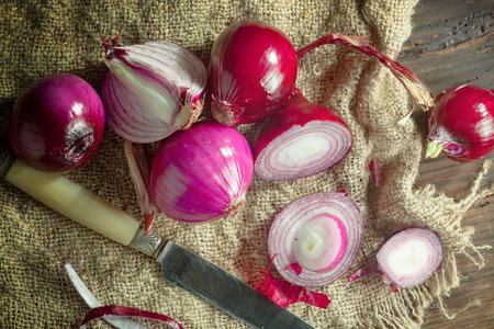 red onions on sackcloth and knife on wooden background, top viewの写真素材