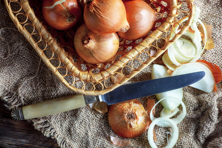 onion in a basket and knife on burlap, top viewの写真素材