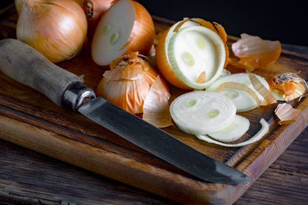 onion and knife on a wooden cutting board. Dark background.の写真素材