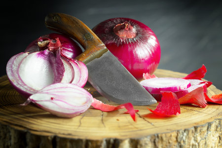red onion and knife on a wooden cutting board on a black background