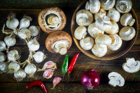 Fresh champignon mushrooms and red hot chili peppers on wooden backgroundの写真素材