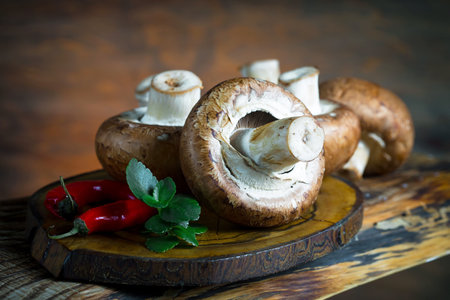 mushrooms champignons on a wooden board with pepper and mintの写真素材