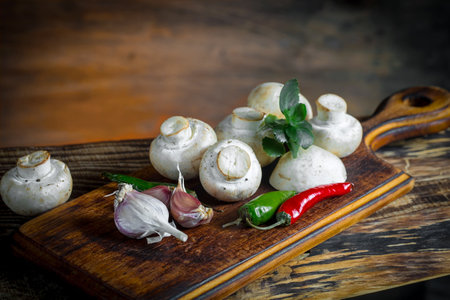 Mushroom champignons on a cutting board on a wooden backgroundの写真素材