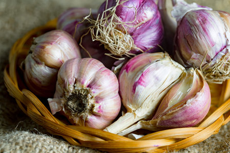Garlic in a wicker basket on a burlap background.の写真素材