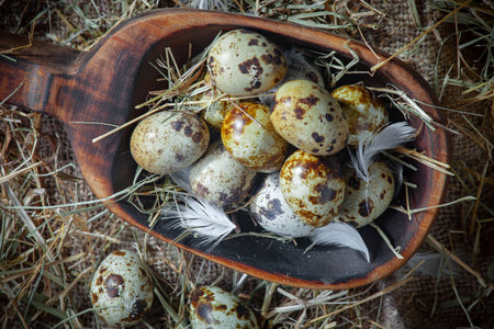 Quail eggs in a wooden bowl on a background of hay.の写真素材
