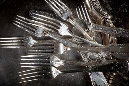 Old silver cutlery on a metal plate. Toned.の写真素材