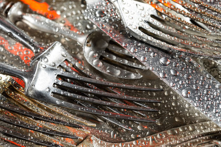 Close up of a bunch of used cutlery with water drops