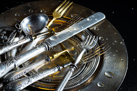 Spoon, fork and knife on a metal plate with water drops
