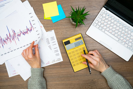 Close-up of a businesswoman working at her desk with a calculatorの写真素材