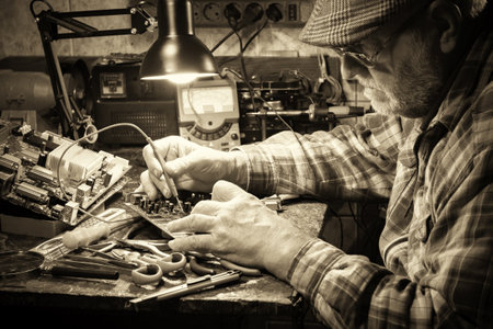 Senior man repairing a computer in his workshop. Selective focus. Toned.の写真素材