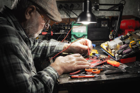 Senior man repairing broken electronic device in home workshop. Selective focus.の写真素材