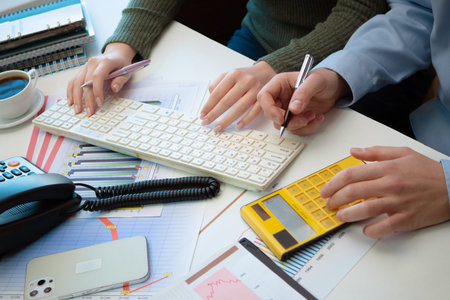 Close up of business people hands using calculator and writing on paper.