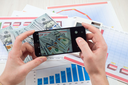 Businessman using a mobile phone to take a photo of money.の写真素材