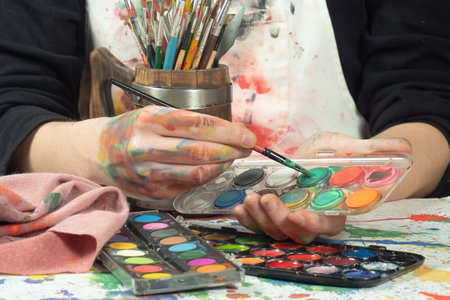 Close-up of artist's hands with paint palette and brushes.の写真素材