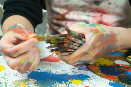 Close up of female hands with paintbrushes and palette of colorsの写真素材