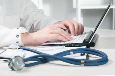 Close-up of a doctor hands typing on laptop computer in the officeの写真素材