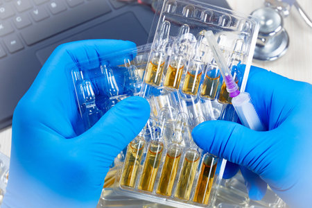 Laboratory technician in blue gloves holding ampoules with samples of vaccine