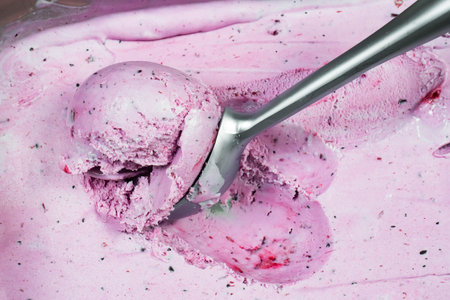 Strawberry ice cream in a bowl with spoon close-up
