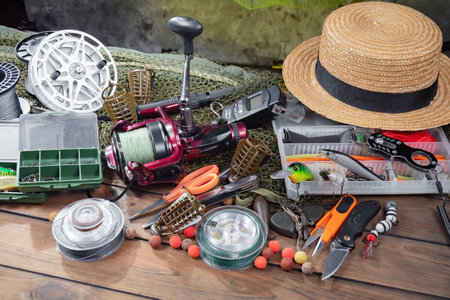 Fishing tackle on a wooden table. Fishing reel, spool, fishing rod, reel, hat and other accessories.の写真素材