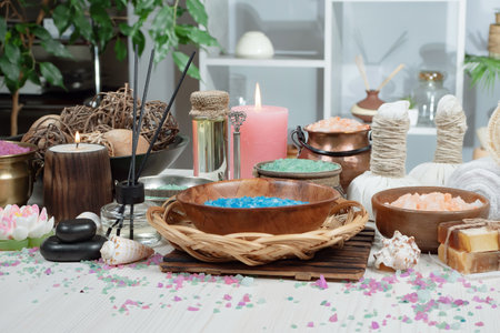 Spa and wellness setting with candles, sea salt, herbal compress balls, towel, towels, candles in a wooden bowlの写真素材