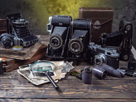 Old camera on a wooden table with old photos and a magnifying glass
