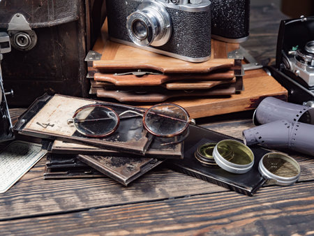 Old camera, glasses, books and other objects on a wooden table
