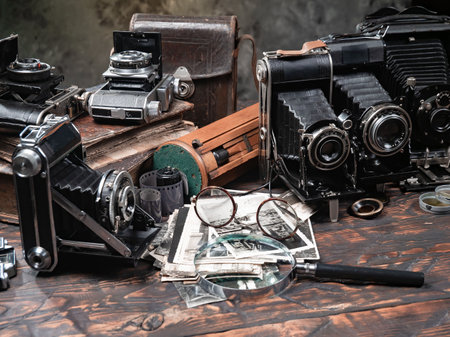 Old camera, magnifying glass and other objects on a wooden tableの写真素材