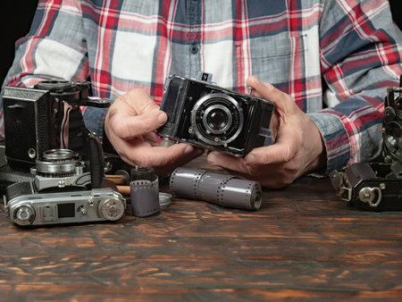 Old camera in the hands of a man on a wooden background.の写真素材