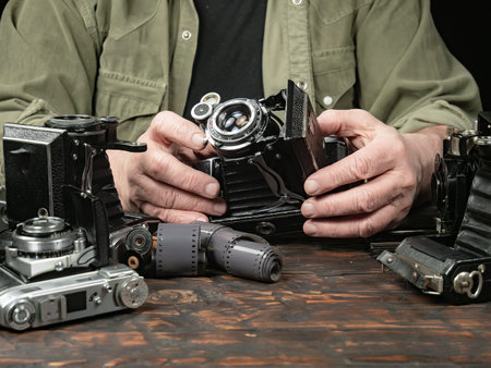 Old camera on a wooden table in the hands of an old photographerの写真素材