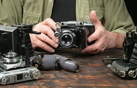 Old vintage camera in the hands of a man on a wooden table