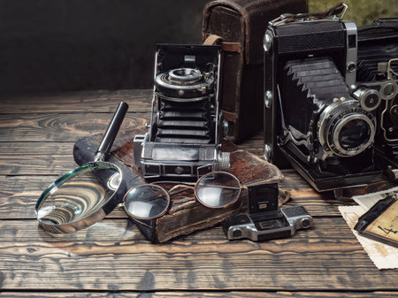 Old camera, glasses and a magnifying glass on a wooden tableの写真素材