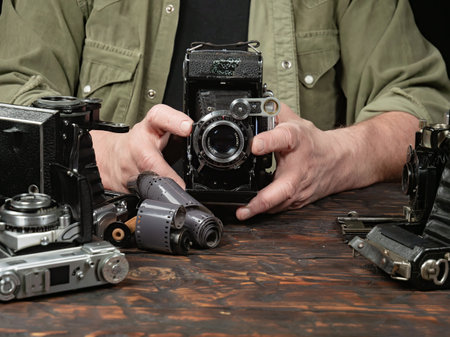 Close-up of a photographer's hands holding a vintage camera.の写真素材