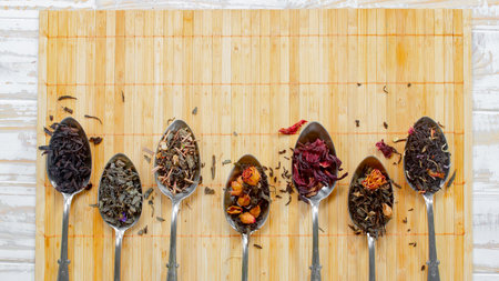 Assortment of dry tea in spoons on wooden background, top viewの写真素材