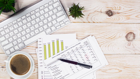 Office desk table with computer, coffee cup and financial report. Top view with copy spaceの写真素材