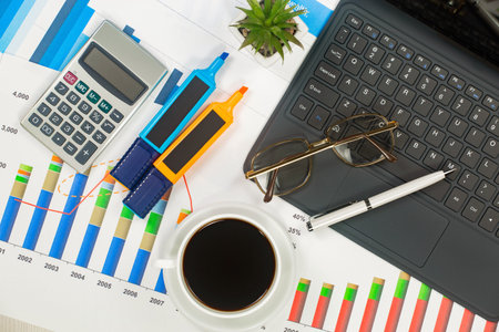 Business workplace with laptop, calculator, coffee cup and graph. Accounting