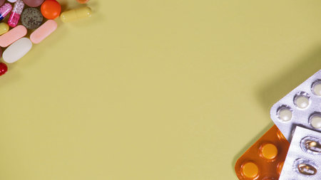 Tablets and capsules on a yellow background with space for text.