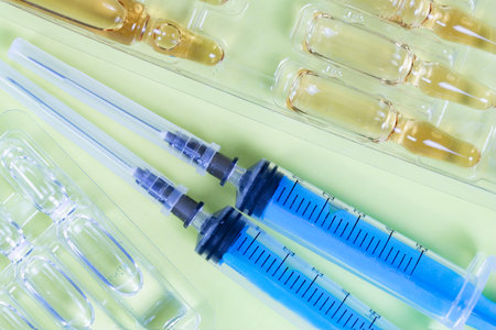 Medical ampoules and syringe on a green background. Close up.の写真素材