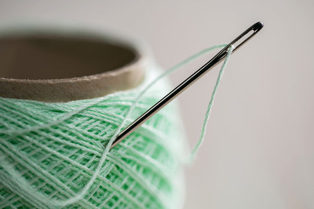 spool of thread and needle on a gray background close-up
