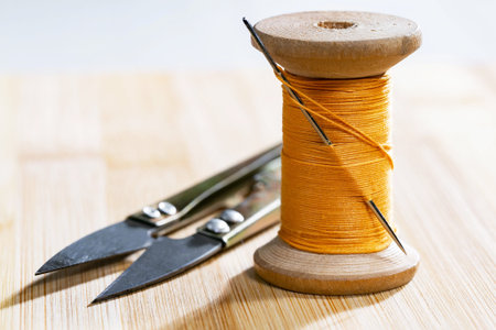 Spool of thread and scissors on a wooden table, closeup