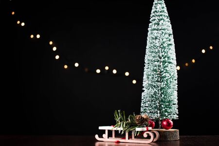 Sprinkle the Christmas tree with snow. Sweets wrapped in a red wrapper. Miniature wooden sleigh.の写真素材