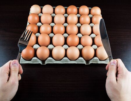 A very hungry man is going to eat a whole tray of eggs. Hungry athlete after a hard workout is going to eat eggs. Eggs are one of the main sources of protein.の写真素材